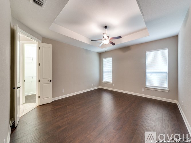 A room with wood flooring and a ceiling fan.