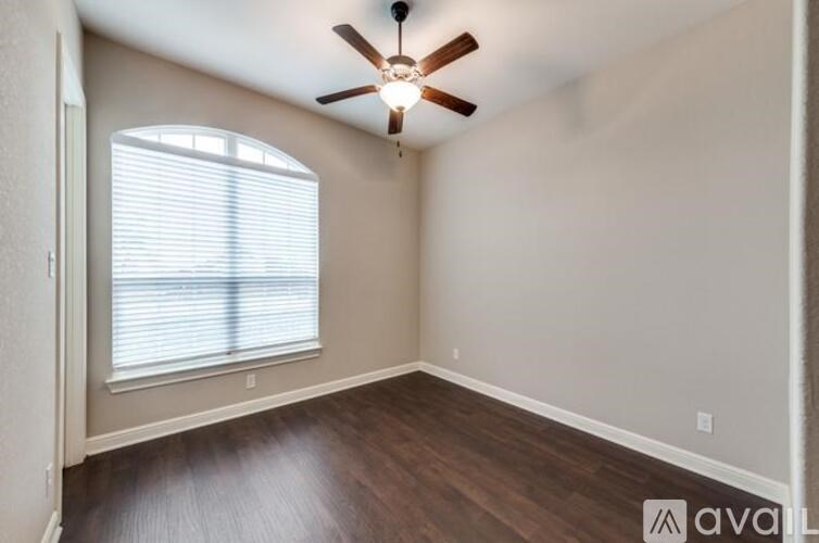 A room with a ceiling fan and a window with blinds.