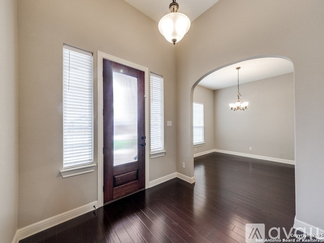 A well-lit room with a wooden floor and a chandelier hanging from the ceiling.