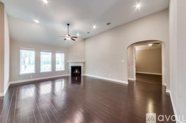 A spacious room with wood flooring and a fireplace.
