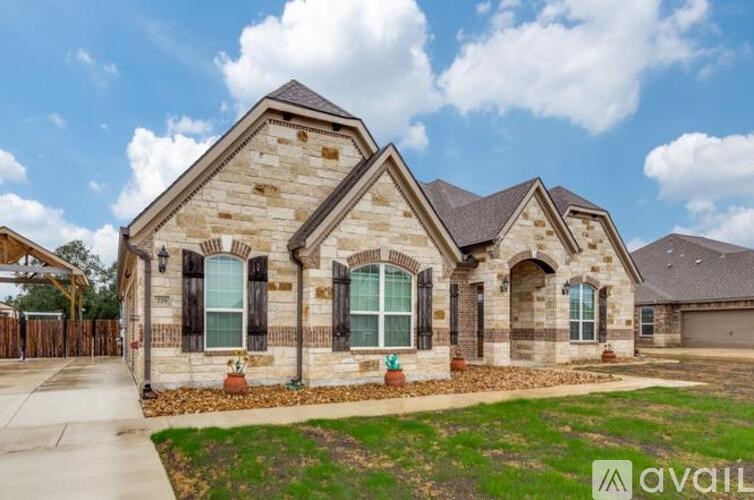 A house with a stone facade and a brown roof is for sale.