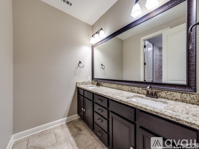 A bathroom with a sink, mirror, and cabinets.