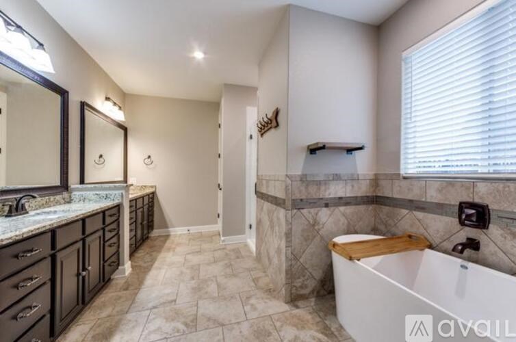 A bathroom with a tub, sink, and mirror.