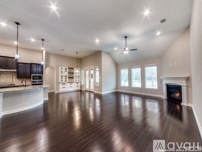 A spacious living room with wood flooring and a fireplace.