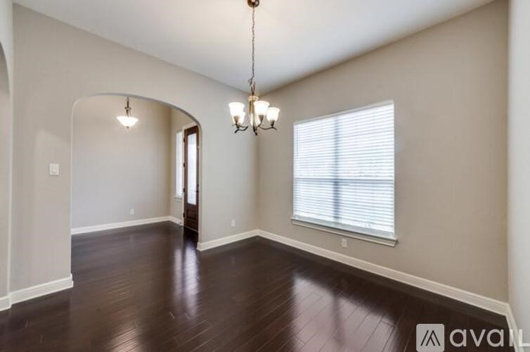 A room with a chandelier and a window with blinds.