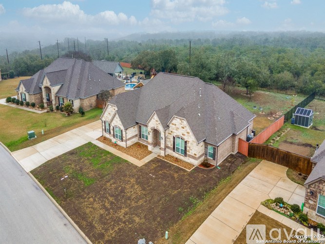 A house with a grey roof and a brown driveway is surrounded by greenery.