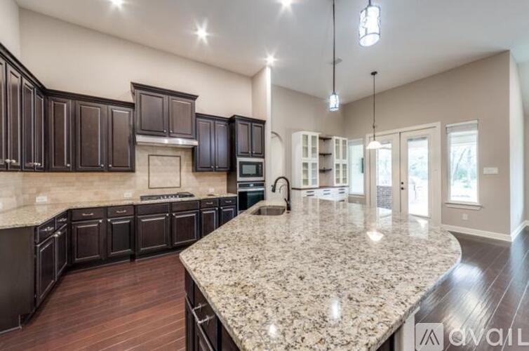 A kitchen with dark brown cabinets and a granite countertop.