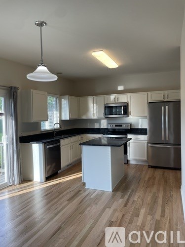 A modern kitchen with wooden floors and stainless steel appliances.