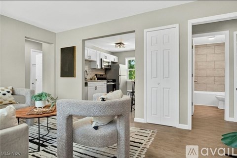 A living room with a grey chair in the foreground and a kitchen in the background.