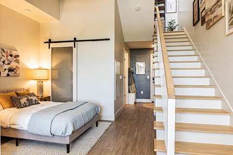A bedroom with a bed, a staircase, and a door.