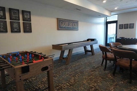 A foosball table is in a room with a pool table and a sign that says "Game Room".