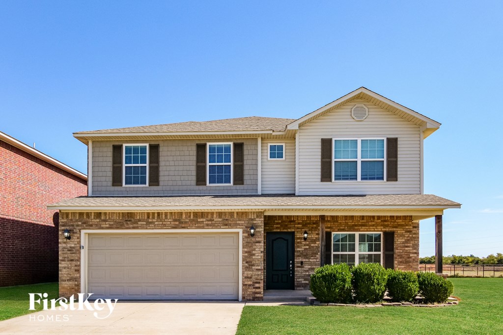 A two-story house with a garage and a brick wall.