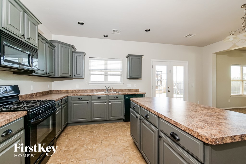 A kitchen with granite countertops and a stove top oven.