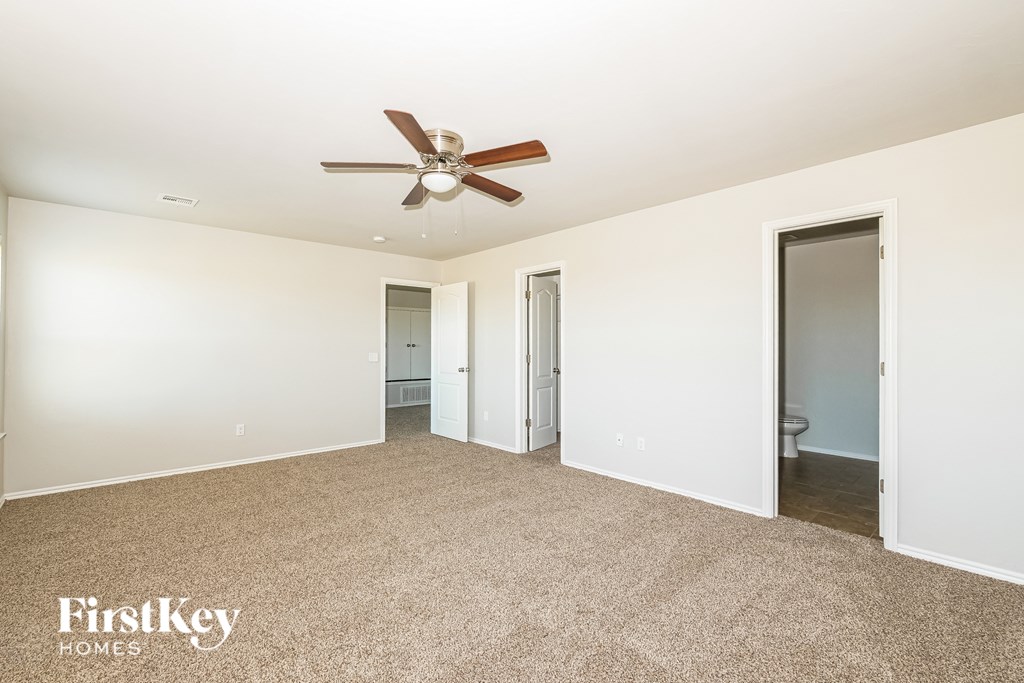 A spacious room with a ceiling fan and carpeted floor.