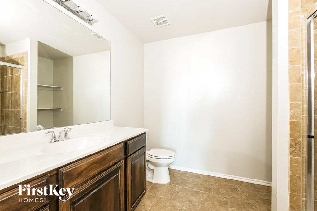 A bathroom with a toilet, sink, and mirror.