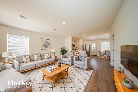 A spacious living room with a grey sofa set and a coffee table in the center.