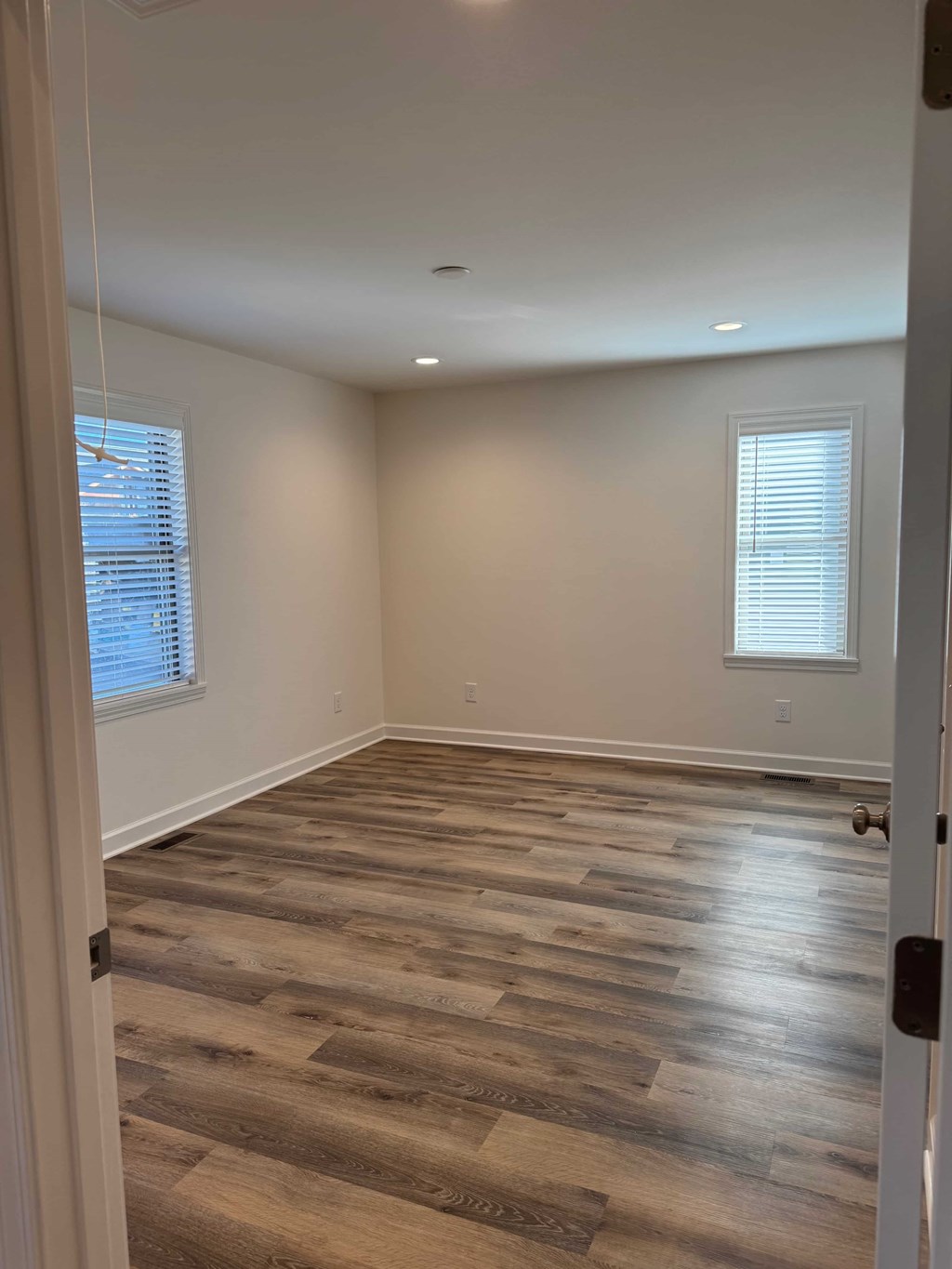 A room with a wooden floor and a window with blinds.