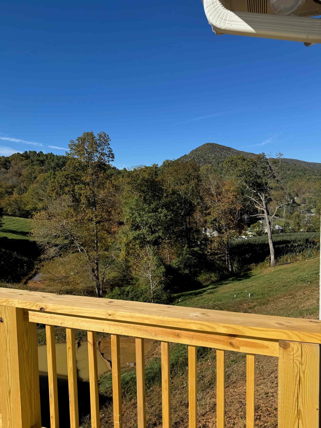 A wooden deck overlooks a lush green valley.