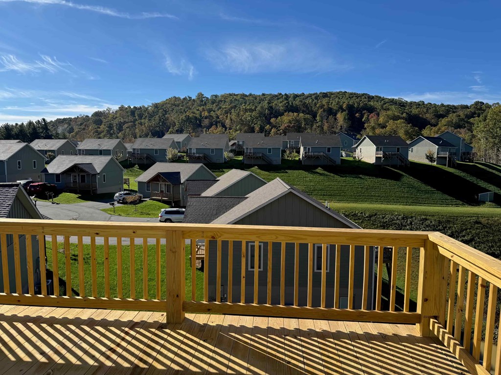 A wooden deck overlooks a residential area with houses and a hill in the background.