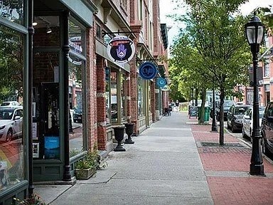 A street with a sidewalk and a row of parked cars.