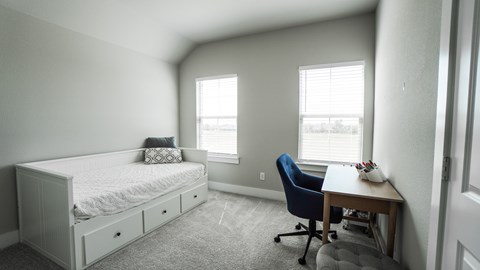 A bedroom with a bed, desk, and chair.