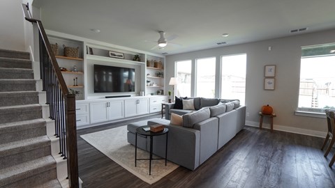 A living room with a grey couch and a television on a cabinet.