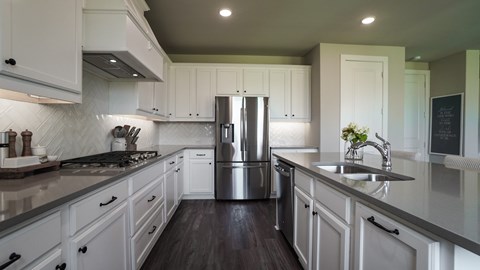 A modern kitchen with white cabinets and a stainless steel refrigerator.