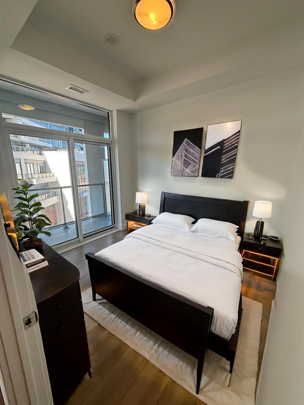 A bedroom with a large bed and a window overlooking a city.