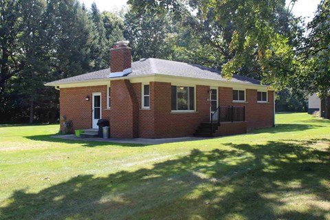 A small red brick house with a white roof and a chimney.