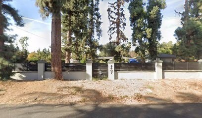 A tree stands in front of a white fence.