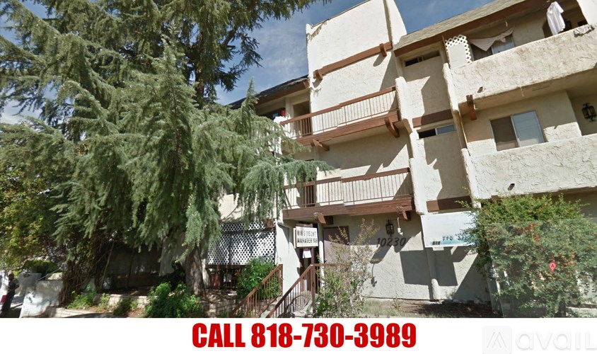 A building with a balcony and a tree in front of it.