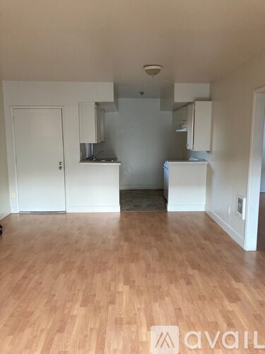 A room with wooden flooring and white walls.