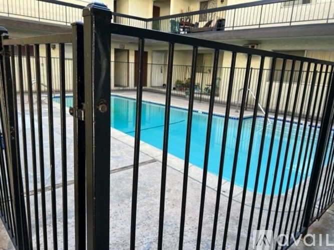 A black metal fence surrounds a blue pool.