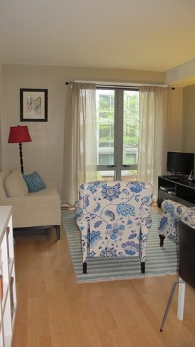 A living room with a blue and white patterned chair and a red lamp.