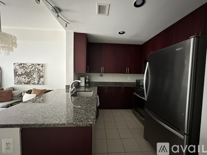 A living room with a television, two chairs, a table with a cup and saucer, and a chandelier.