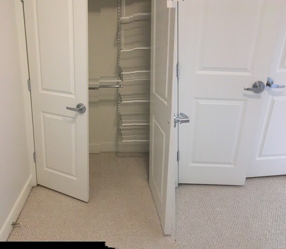 A white door is open to a hallway with a carpeted floor.