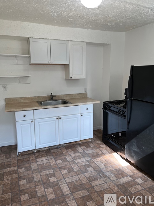 A kitchen with white cabinets and a black microwave above the sink.