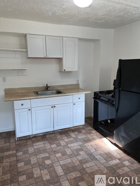 A kitchen with white cabinets and a black microwave above the sink.