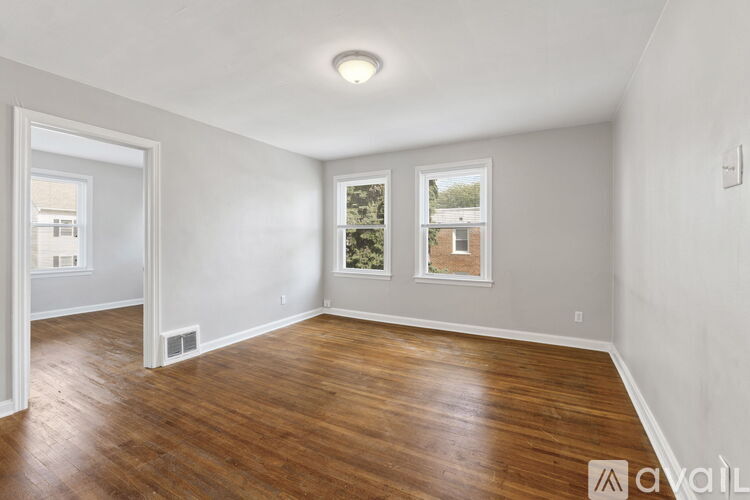 A spacious room with wooden floors and white walls.