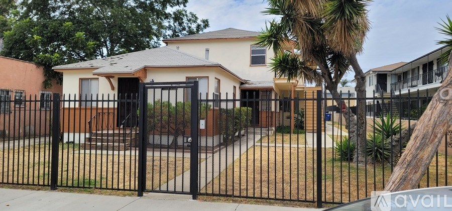 A house with a black fence and a tree in front.