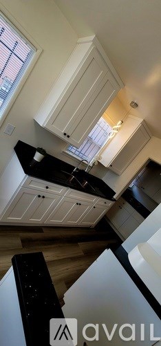 A kitchen with white cabinets and a black countertop.