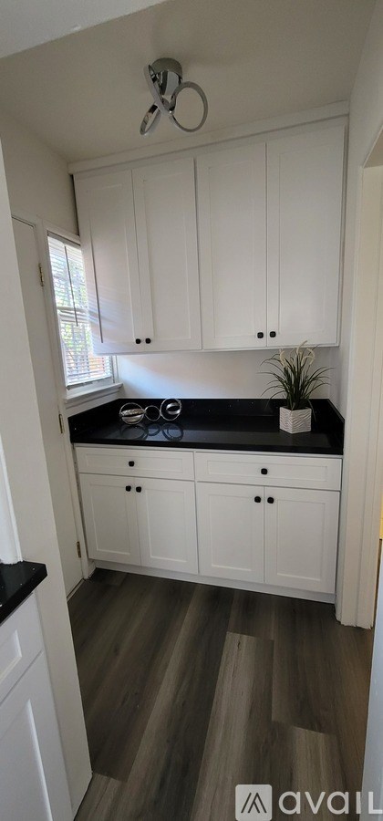 A kitchen with white cabinets and a black countertop.