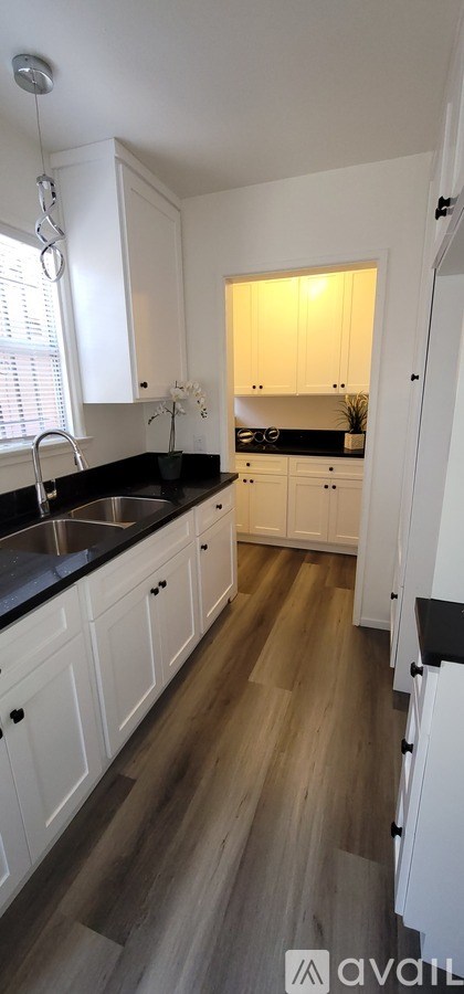 A kitchen with white cabinets and a black countertop.