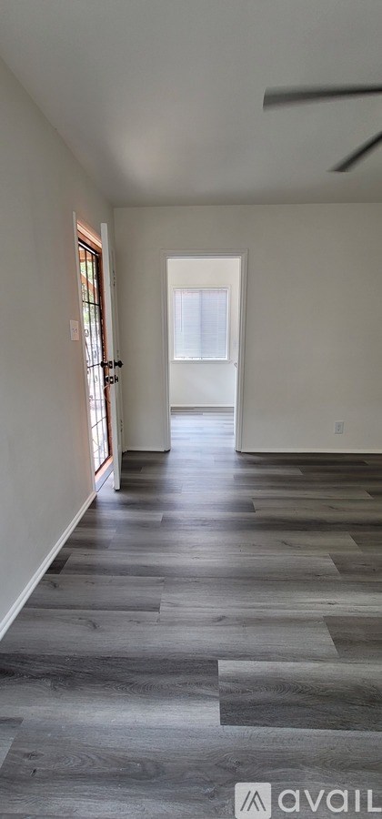 A room with a wooden floor and a door in the distance.