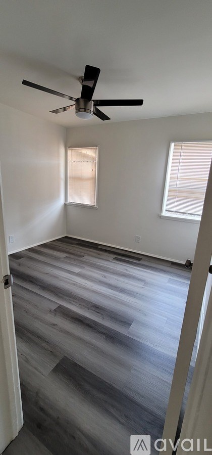 A room with a ceiling fan and two windows.