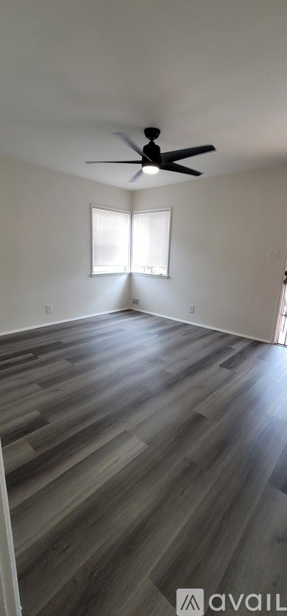 A room with a ceiling fan and a window with blinds.