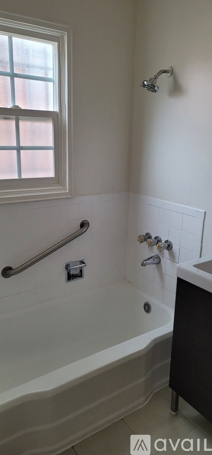 A bathroom with a tub, sink, and window.