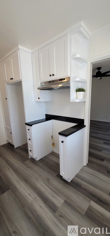 A kitchen with white cabinets and a black countertop.