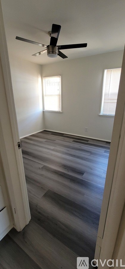 A room with a ceiling fan and wooden flooring.