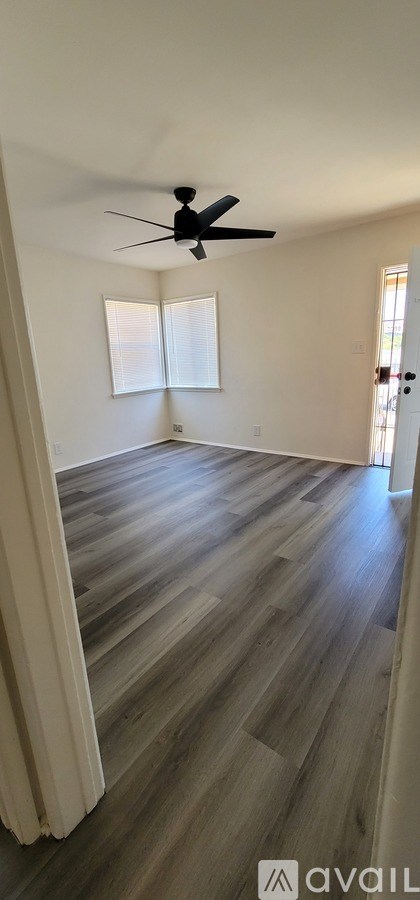 A room with a ceiling fan and wooden flooring.
